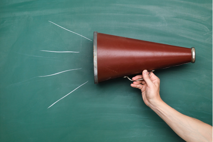 brown megaphone in front of a green chalkboard